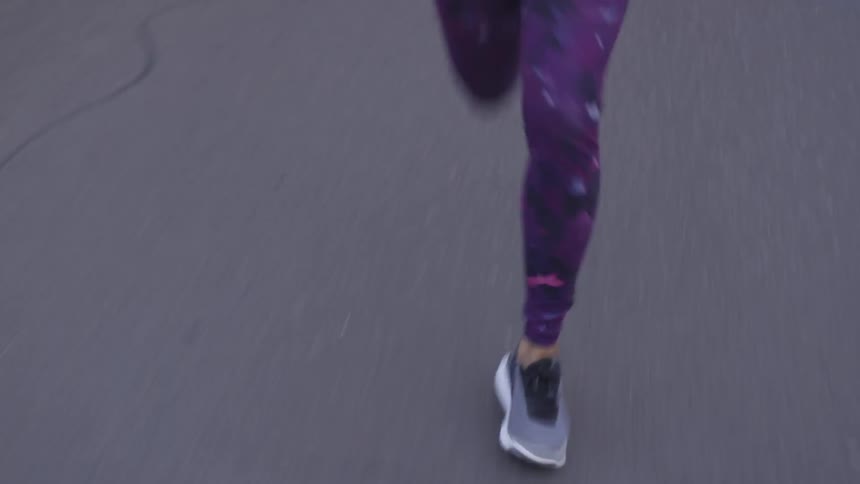A person jogs down the road wearing tights