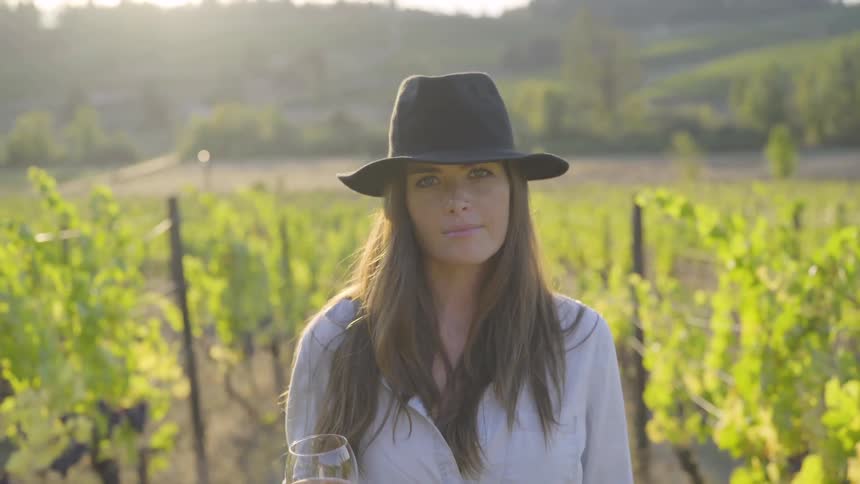 A woman is outdoors holding a drink