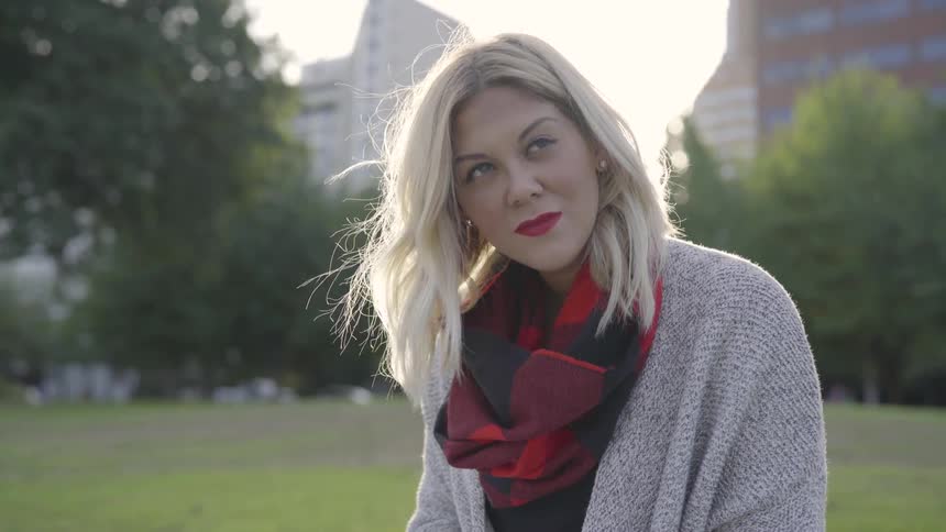 Woman stands in the park and looks up at the sky