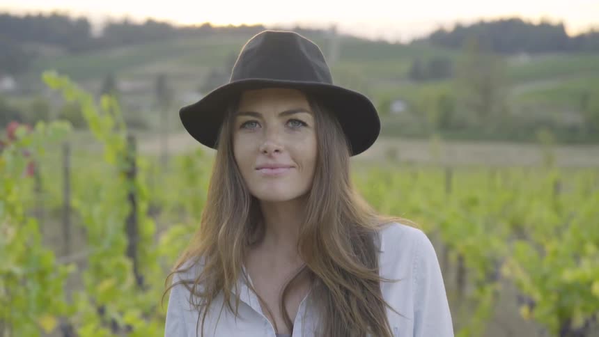 A young woman walks through a vineyard