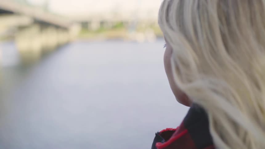 A blonde white woman looks across a body of water