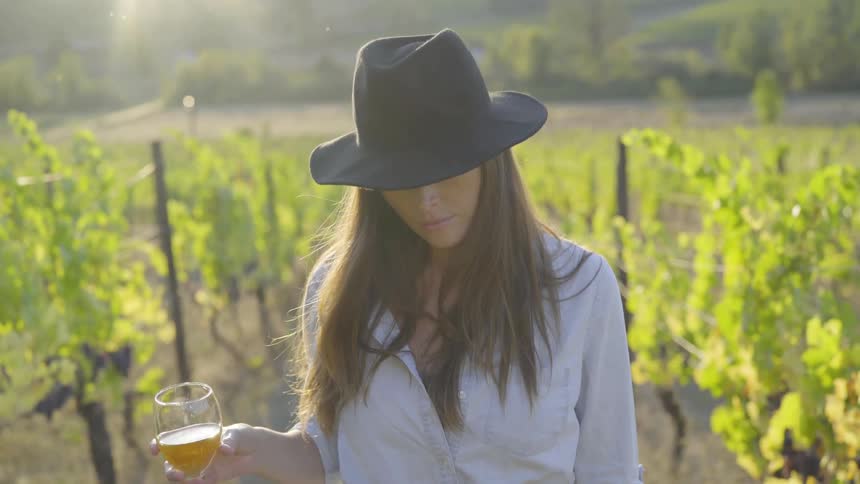 A woman is outdoors while holding a glass