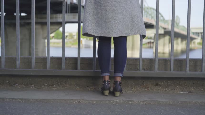 Person stands at railing looking out at a lake with a bridge