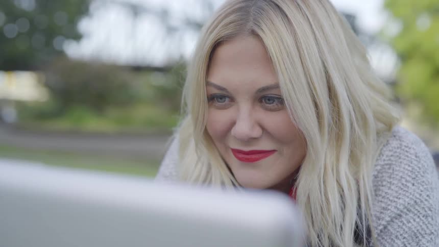 A woman laughing at a computer screen