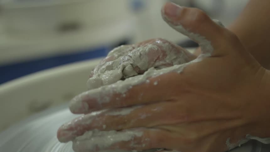 A woman is working with clay on a pottery wheel