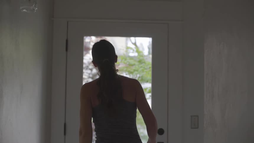 Woman stretches near front door of house