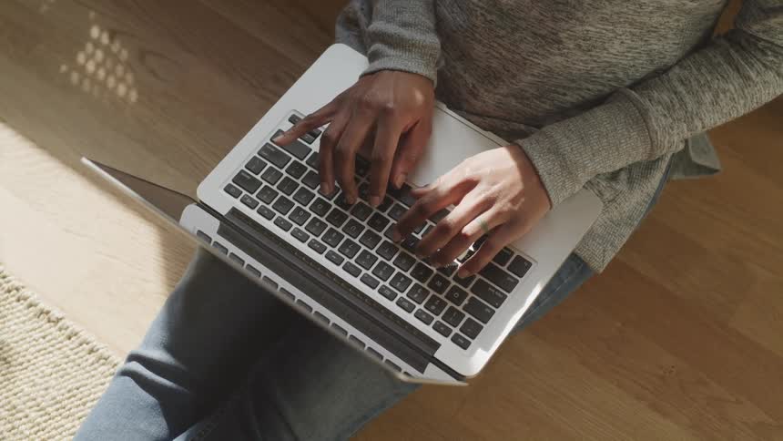 A person is typing on a laptop indoors