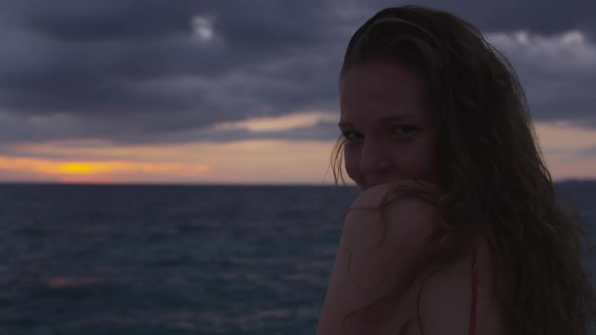 Woman looks away from sun rising on horizon