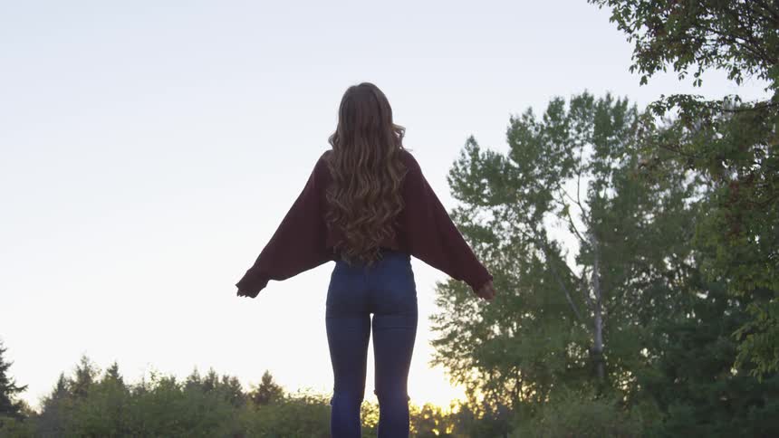 A woman stands in a clearing meditating in the early morning