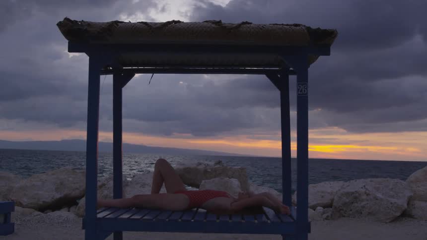 A woman lays in the gazebo on the beach