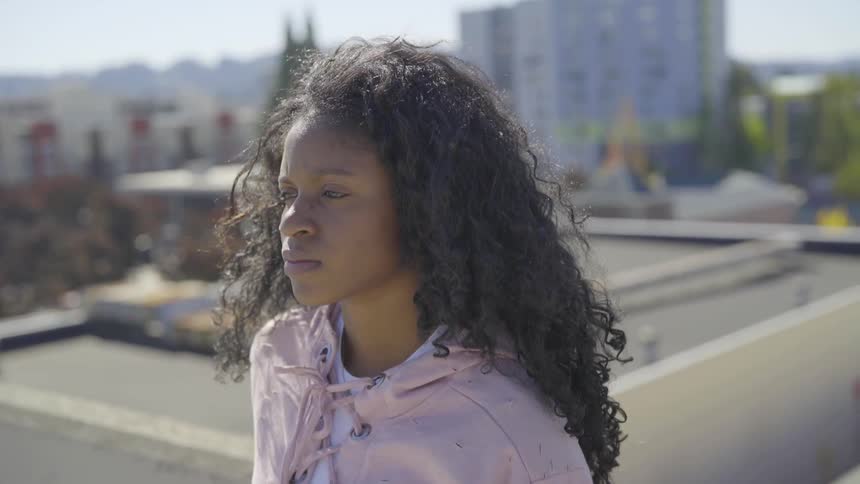 A young woman contemplates while on a rooftop