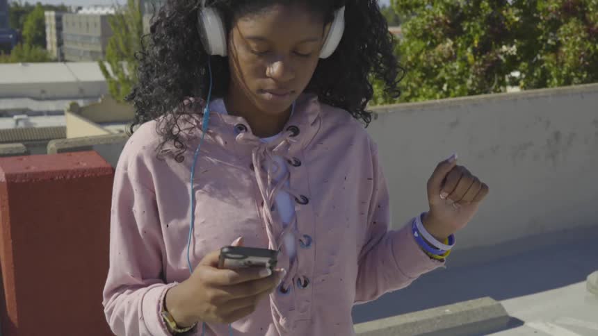 A girl dances on a parking garage to the music playing on her headphones