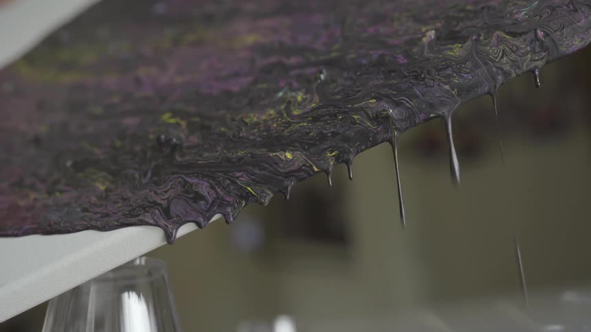 Dark paint dripping off a utensil