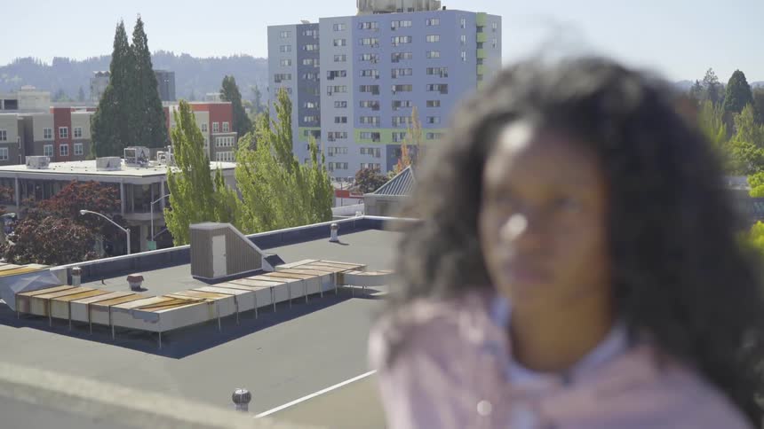 Woman stands on a rooftop looking around