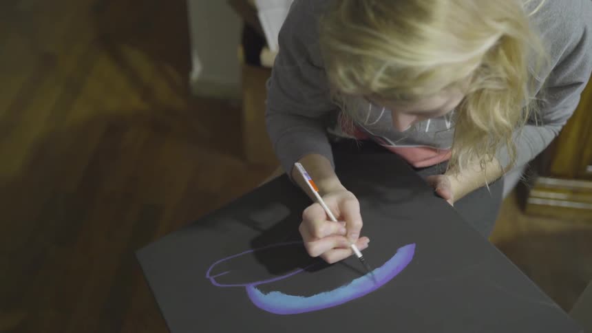 Girl painting on a black canvas