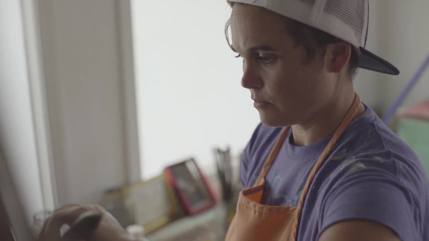 Woman in a cap and apron painting a canvas