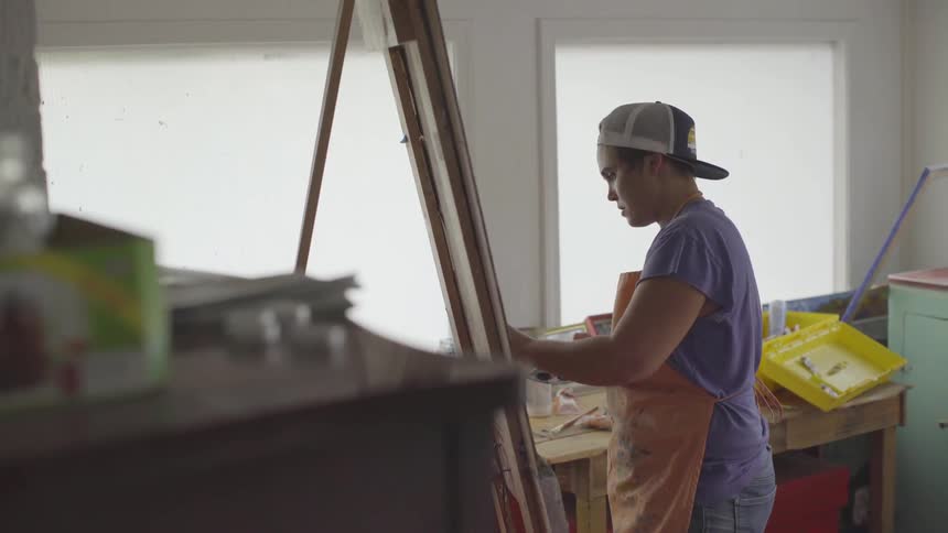 Person paints on a canvas in a studio