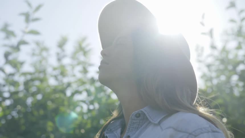 Woman in hat looks up at sky looking content