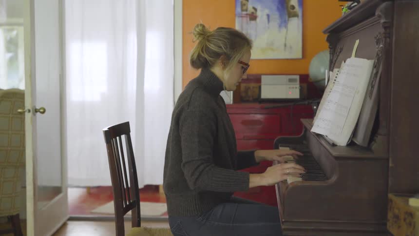 Woman plays a piano in a house