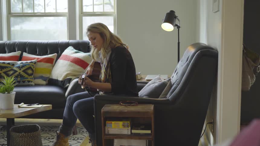 A woman is playing guitar indoors