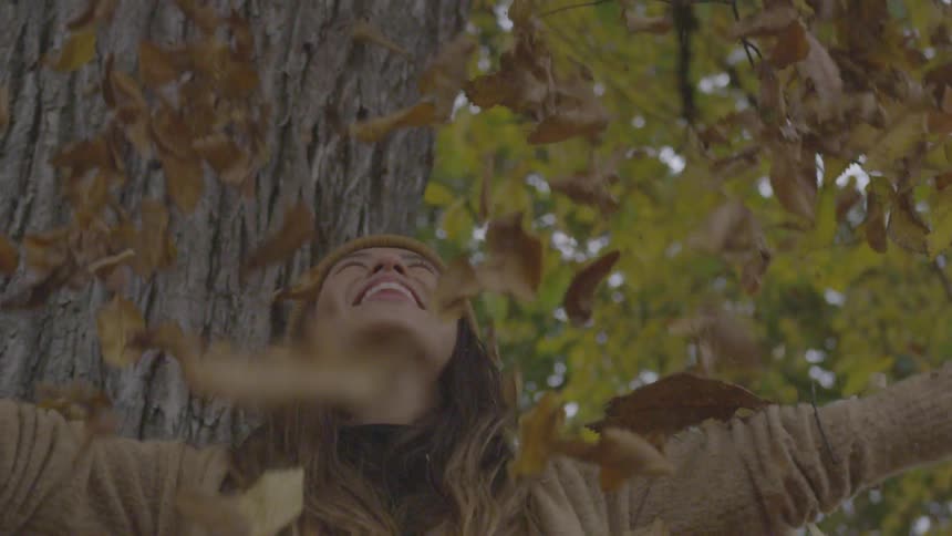 A woman throws leaves over her head