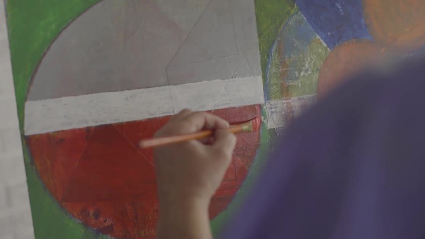 A person making a stroke with red paint on a painting