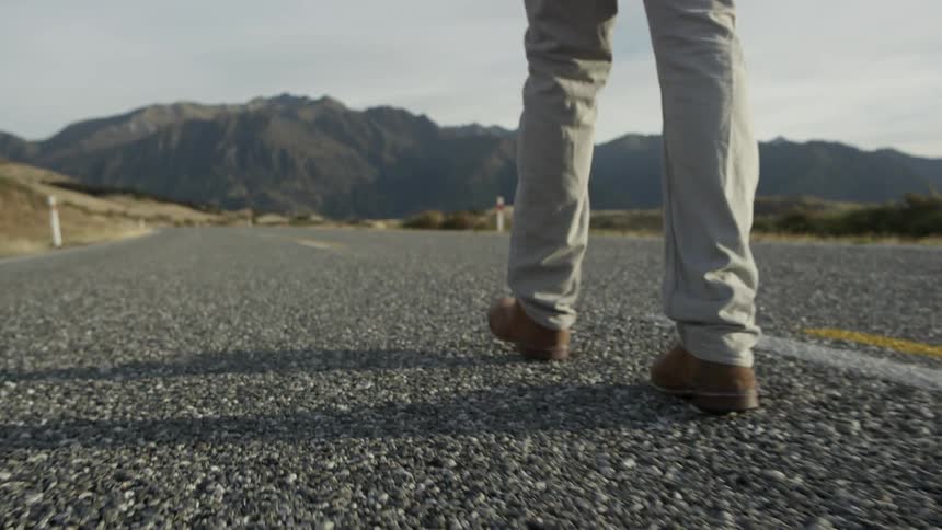Man walks down the middle a deserted rural road