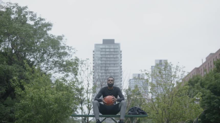 Man sits on bench holding basketball