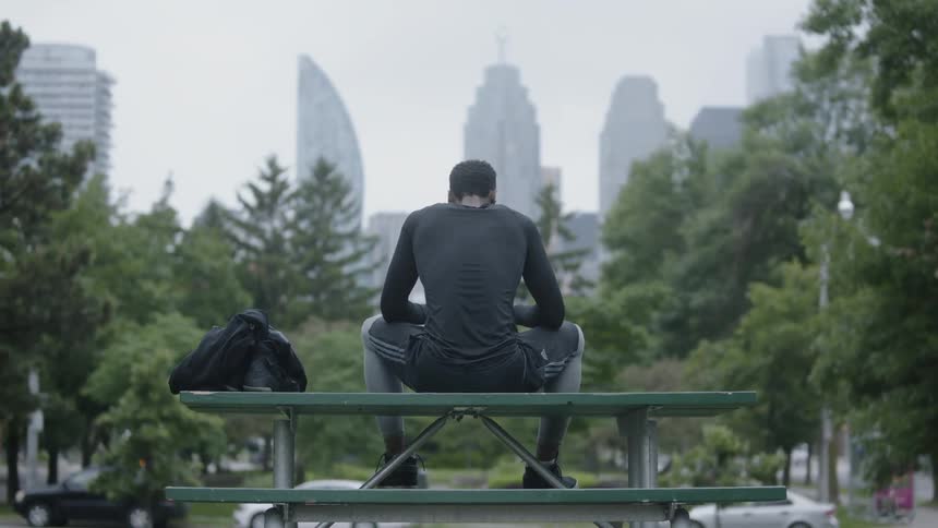 Man sits down against the skyline of the city on a cloudy day