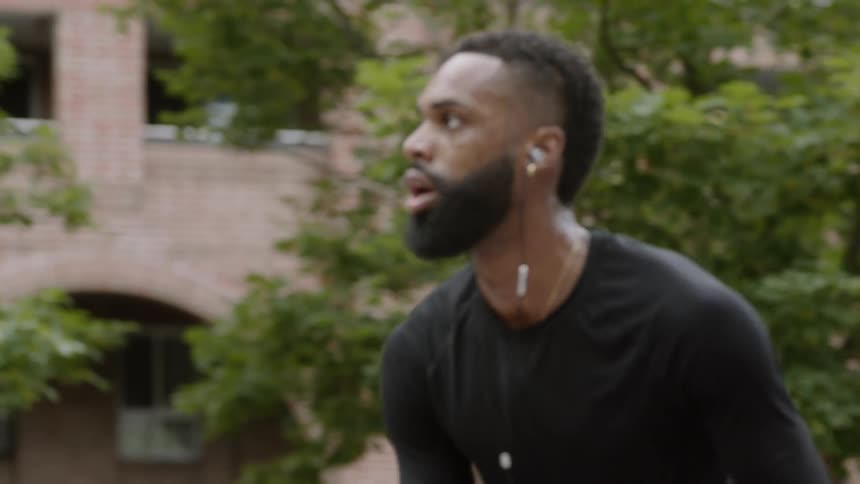 A man playing basketball on a court surrounded by trees