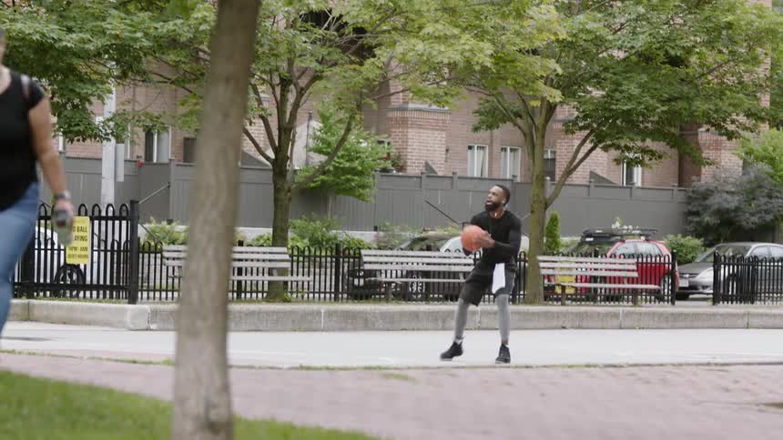 A man dribbles a basketball then shoots it
