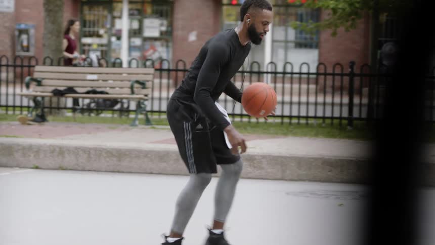 Man plays with basketball on court in park