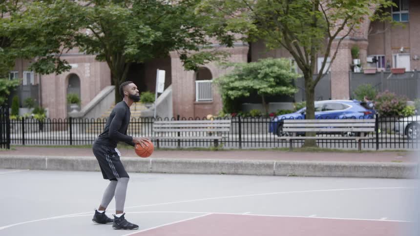 A man dribbles a basketball and throws it