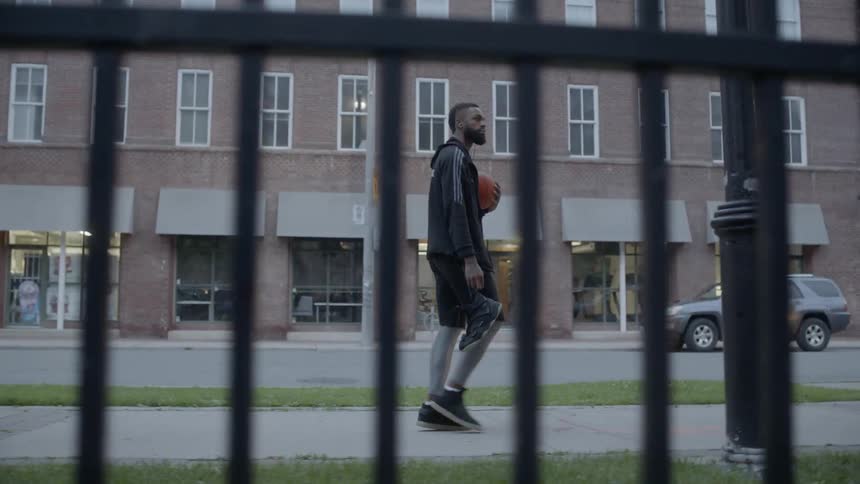 Bearded black man walks down the street in the city center at dusk