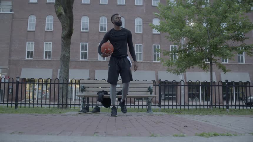 Man stands up from bench holding basketball