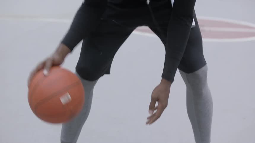 Bearded black man wearing earphones plays basketball in the basketball field by day