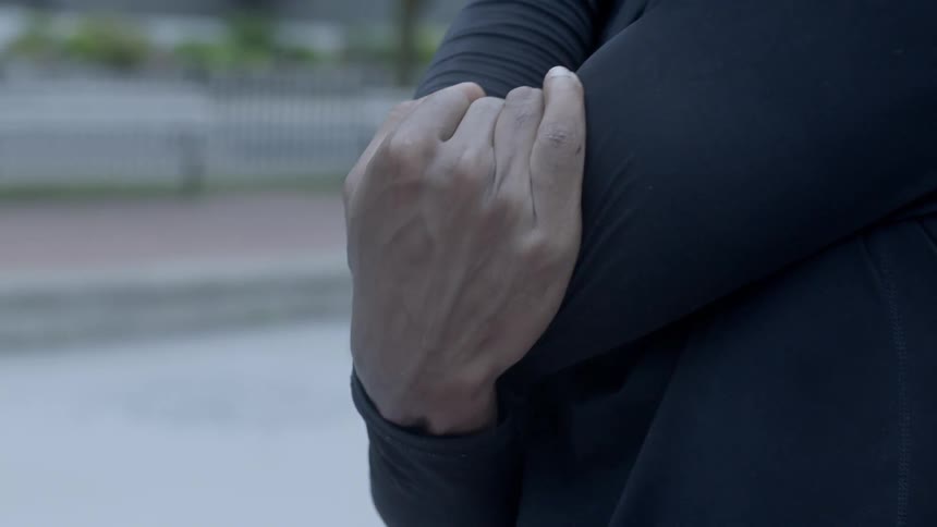 Black male in a long sleeve workout shirt stretching