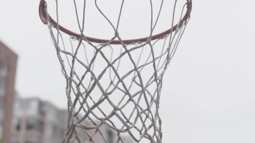 Basketball is being shot towards hoop on a cloudy day