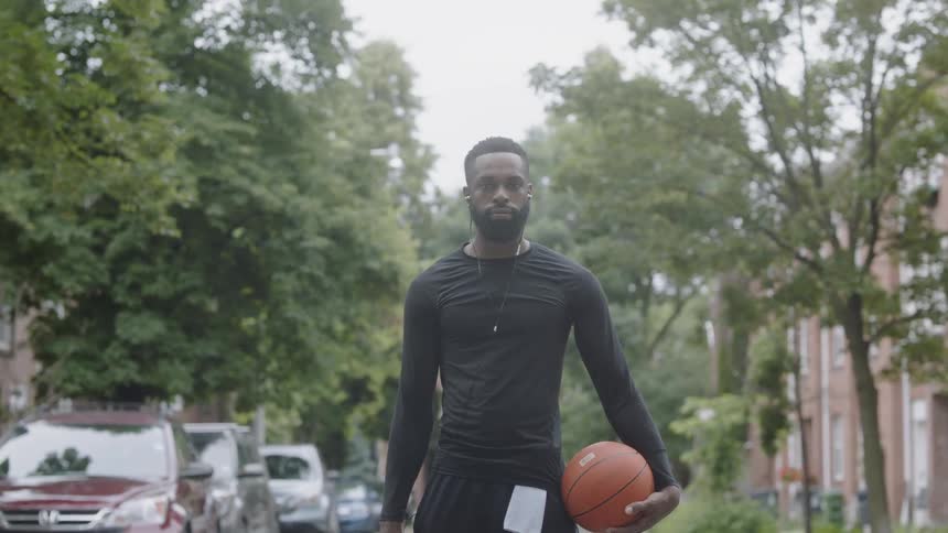Man stands staring while holding basketball