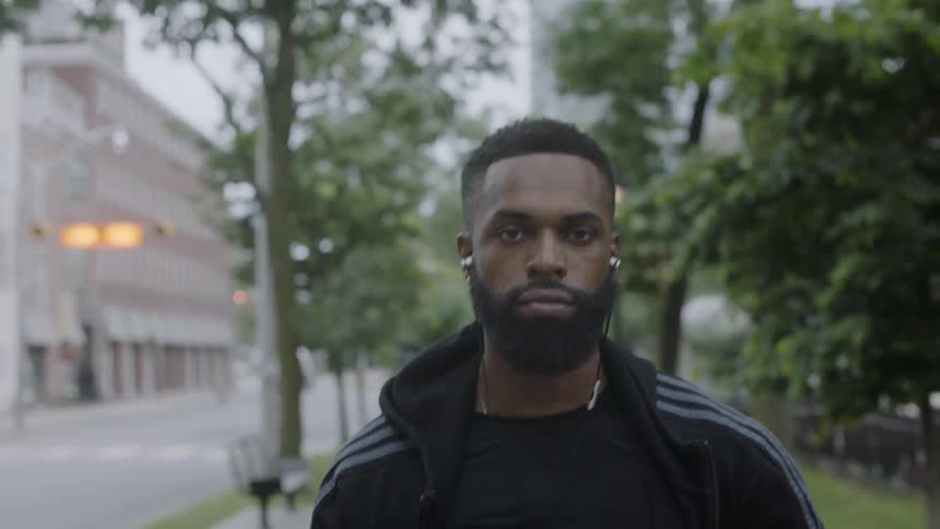 Man walking down a street in sportswear listening to music on headphones