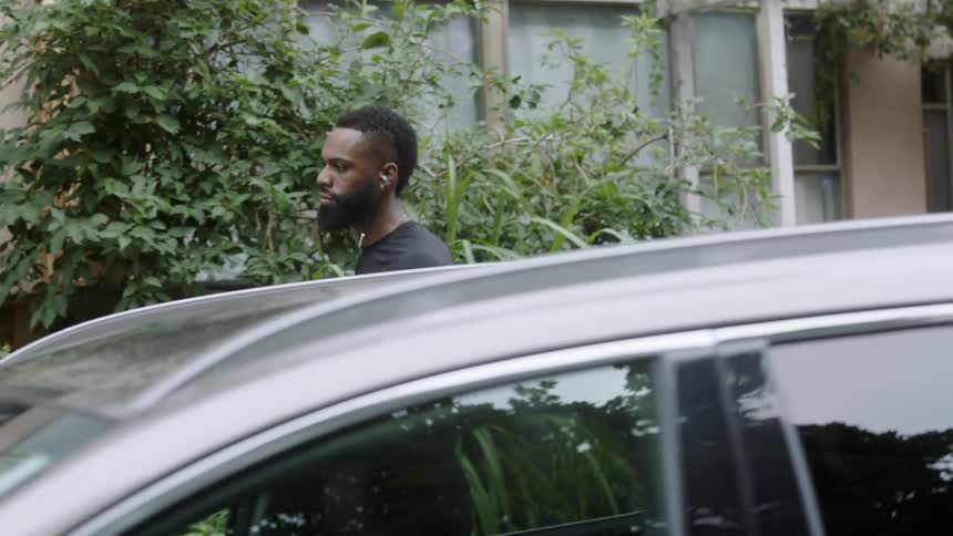 Man walks down a sidewalk carrying a basketball