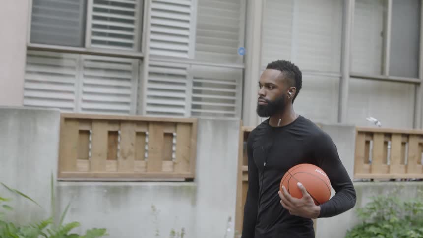 Black man walks on the street holding a basketball ball in his hands