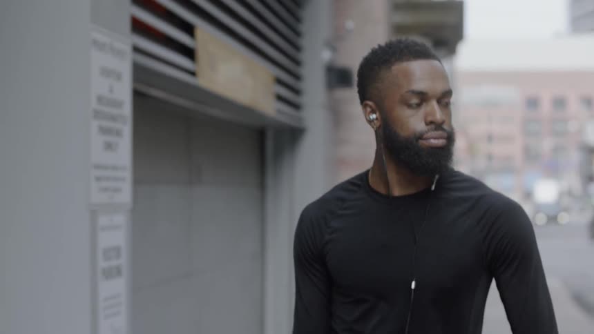 Man wearing earbuds walks down the city street