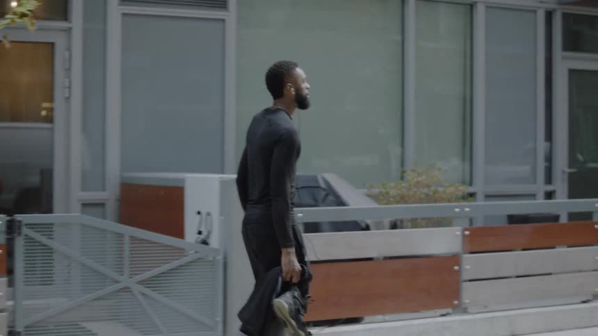 Man walks dribbling basketball and carrying shoes and jacket