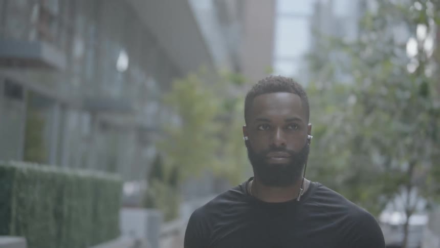 Black man walking down the street listening to music on his earphone