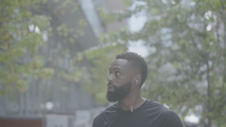 A man walking down a city street holding a basketball