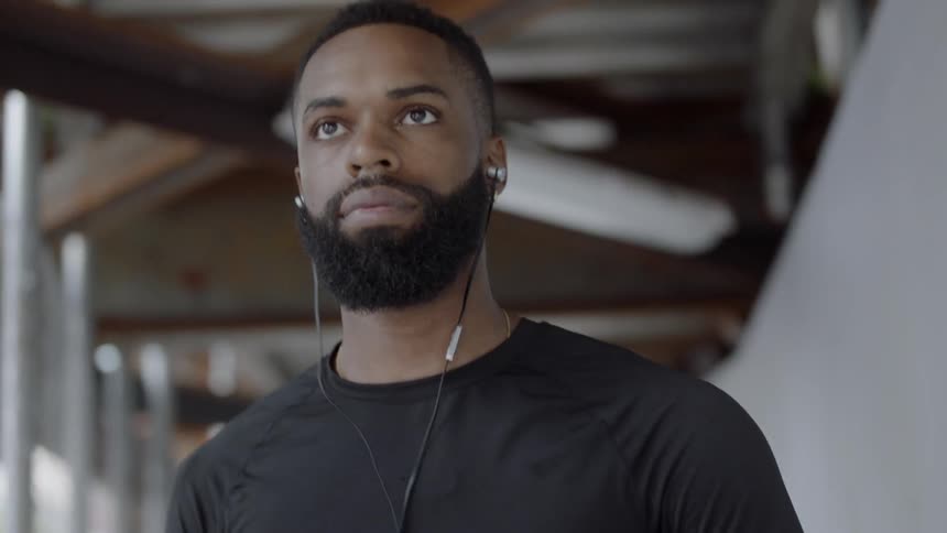 Black man walking listening to music and holding a basketball