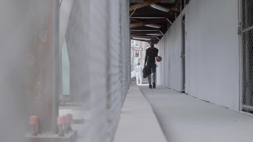 Man bouncing a ball in a hallway