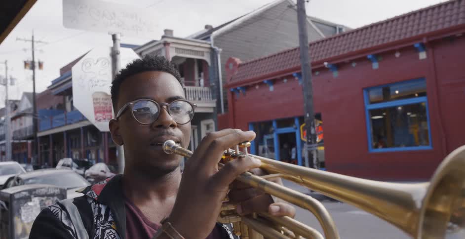 Man plays the trumpet while standing on the sidewalk