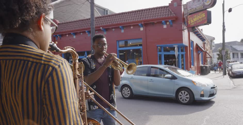 Three young black men play musical instruments on a street corner